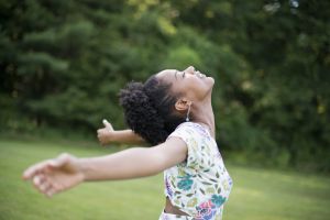 A young woman in a summer dress with her arms outstretched, celebrating freedom.