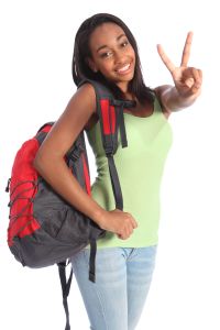 V for victory success by pretty young African American teenager school girl, with long black hair wearing green t-shirt and red school backpack with beautiful smile.