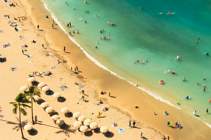 High Angle View Of A Tropical Beach With Peple Enjoying The Sun And The Warm Waters Of The Ocean